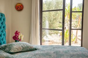 a bedroom with a bed and a large window at Les jardins de Mogador, La Villa Cactus in Essaouira +10 photos