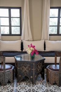a living room with a couch and a table with flowers on it at Les jardins de Mogador, La Villa Cactus in Essaouira
