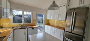 Una cocina con gabinetes blancos y un refrigerador de acero inoxidable. en Havre de paix près des plages, en Arzon