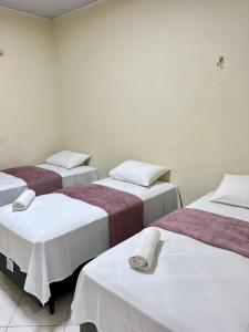 Zimmer mit 3 Betten mit weißer und roter Bettwäsche in der Unterkunft Casa Açaí in Bragança