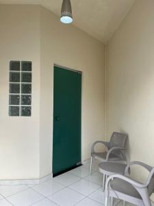 ein Raum mit zwei Stühlen und einer grünen Tür in der Unterkunft Casa Açaí in Bragança + 1 Foto