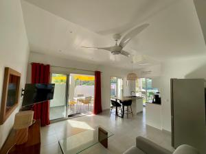 Una sala de estar con un sofá y un ventilador de techo. en Appartement Kay Nephile - vue mer - Grande Anse, en Les Anses-dʼArlet