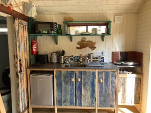a kitchen with blue wooden cabinets and a sink at The Old Shed in Benderloch