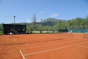 two people playing tennis on a tennis court at Pensjonat Szczebel in Mszana Dolna