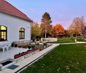 a house with a yard with a table and a garden at Fehér Bagoly Vendégház in Kovácsszénája