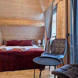 a bedroom with a bed and a chair and a table at Domki Wojtasówka in Obrazów
