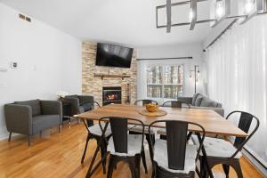 a dining room with a table and chairs and a fireplace at Chez Dodo Chalet Tremblant 3bdrs condo with fireplace in Mont-Tremblant