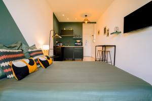 a bedroom with a large green bed with pillows at Le studio tendance in Albi