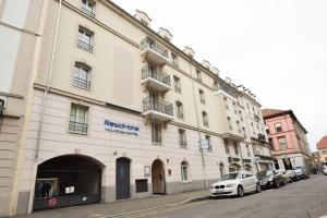 un grand bâtiment blanc avec des voitures garées devant lui dans l'établissement Residhotel Mulhouse Centre, à Mulhouse