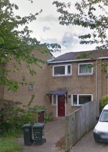 ein Backsteinhaus mit einer roten Tür und zwei Mülltonnen in der Unterkunft Hamilton House -3 bed Close to Town, Drive Parking, 2 toilets in Newcastle upon Tyne