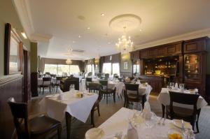 um restaurante com mesas e cadeiras brancas e um lustre em Hatton Court Hotel em Gloucester