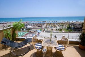 eine Terrasse mit einem Tisch und Stühlen sowie einem Strand in der Unterkunft Carihuela Beach Apartamentos in Torremolinos