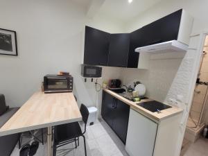 Una pequeña cocina con gabinetes negros y una encimera. en Logement entier Pantin, en Pantin