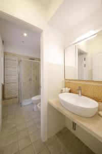 un bagno con lavandino, WC e specchio di L'arco di San Giuseppe a Siracusa