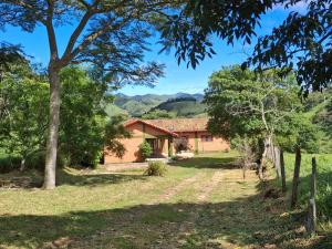 a house in the middle of a field with trees at Caminho da Toca in Passa Quatro