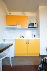 a kitchen with yellow cabinets and a microwave at Residhotel Lyon Lamartine in Tassin-la-Demi-Lune