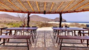 a group of tables and chairs under a wooden umbrella at Entire Villa Private Beach Front Oasis at Punta Lobos - Casa Punta Lobos in Todos Santos