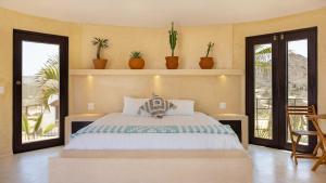 ein Schlafzimmer mit einem Bett mit Pflanzen an der Wand in der Unterkunft Entire Villa Private Beach Front Oasis at Punta Lobos - Casa Punta Lobos in Todos Santos