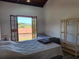 a bedroom with a bed and a large window at Caminho da Toca in Passa Quatro