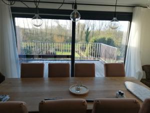 a dining room table with chairs and a large window at Vakantiewoning Yade in Zwalm