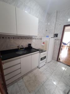 a white kitchen with a sink and a refrigerator at Apê com 2 quartos super bem localizado em copa in Rio de Janeiro