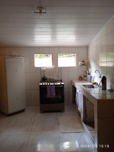 a small kitchen with a stove and a sink at Chácara Acolhedora! in Majé +10 photos