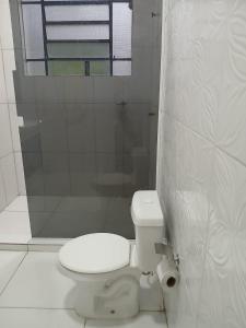 a white bathroom with a toilet and a shower at Chácara Acolhedora! in Majé