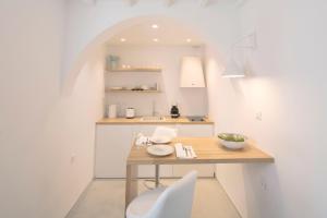 a white kitchen with a table and a white chair at Beyond Blue Suite in Mýkonos City