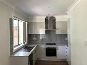 a kitchen with white cabinets and a sink and a window at New stand-alone 2-bedroom house in Baulkham Hills