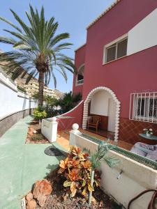 una casa roja con una palmera delante de ella en amazing apt Playa del Cura, en Mogán