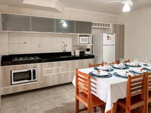 una cocina con mesa con sillas y una cocina con una mesa blanca en Flamingo - 4 suite -15 gasten - Arraial d' Ajuda, en Porto Seguro