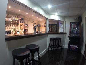 a bar with three stools in a bar with a mirror at Happy Return Hotel in Blackpool
