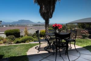 a table and chairs on a patio with a palm tree at Grandview Guesthouse in Cape Town