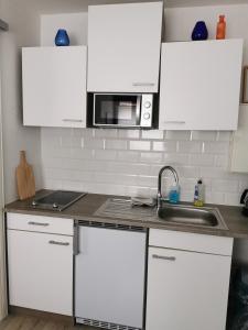 a kitchen with white cabinets and a sink and a microwave at Günstige, schöne Ferienwohnung im Wanderparadies in Wernigerode +6 photos