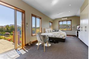 una camera da letto con un letto, un tavolo e finestre di Studio Nestled in Ridgecrest a Wanaka