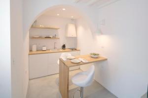 a white kitchen with a desk and a chair at Beyond Blue Suite in Mýkonos City