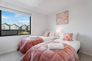 deux lits dans une chambre avec une grande fenêtre dans l'établissement Stylish & Modern Wanaka Townhouse - Your Dream Holiday Awaits, à Wanaka
