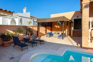 a woman sitting in chairs next to a swimming pool at Villa Deva 20 in Torrevieja