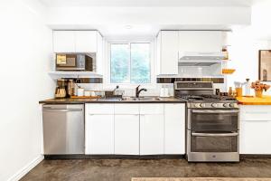 a kitchen with white cabinets and stainless steel appliances at Luxury Old Town Winter Retreat- Hot Tub and Games in Niagara on the Lake