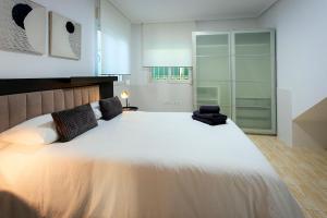 a bedroom with a large white bed and a chair at Villa Deva 20 in Torrevieja +51 photos