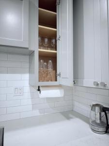 a white kitchen with a cupboard with wine glasses at Modern Family Haven - Minutes from Disney Magic-OC in Midway City