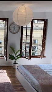 a room with a bed and a clock and windows at Studio cocoon hypercentre Carré d'or de Strasbourg in Strasbourg