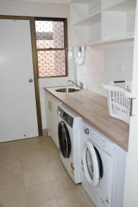 a kitchen with a washing machine and a sink at Seaview Townhouse 2 - Bring your own linen. in South West Rocks