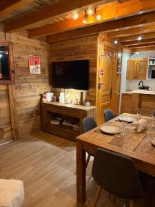 een eetkamer met een tafel en een televisie bij Chalet Cosy Les Gets Vue Montagne in Les Gets
