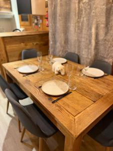 een houten tafel met borden en wijnglazen erop bij Chalet Cosy Les Gets Vue Montagne in Les Gets