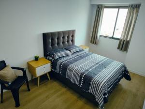 a bedroom with a bed and a chair and a window at Depa Bonito en Condominio ! in Tacna