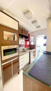 a kitchen with wooden cabinets and a counter top at Apartamento Top Centro de Tubarão in Tubarão