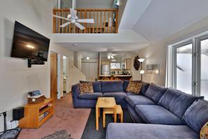 a living room with a blue couch and a table at Woods Resort and Spa - Cozy 2-Bedroom Condo Minutes to Ski Resort - Spa, Pool, Hot Tub, Tennis, Fireplace in Killington