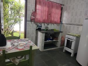 a kitchen with a table and a sink and a stove at Pousada Porto Aventura - Chalés da Luci -Guaraú 13-98159-2115 in Peruíbe