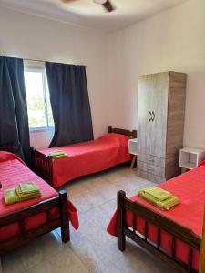 a room with three beds with red sheets and a window at San rafael del diamante apartamentos in San Rafael +24 photos